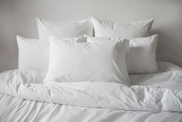 White pillows, duvet and duvetcase in a bed. Side view.