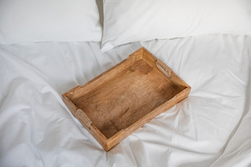 Rustic wooden tray on a white bed. Romantic breakfast in a bed.