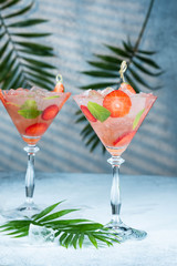 Strawberry lemonade or alcoholic cocktail with ice syrup soda and mint leaves on bar table.