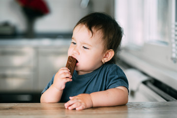 little girl in the afternoon in the kitchen eating a delicious chocolate bar