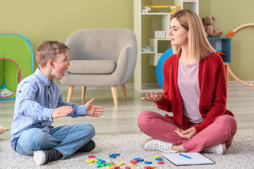 Female psychologist working with boy suffering from autistic disorder