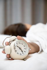 Woman pressing alarm clock in the morning
