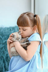 Girl with cute fluffy kitten near window