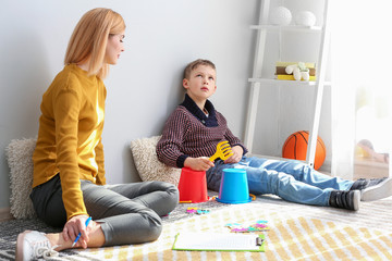 Female psychologist working with boy suffering from autistic disorder