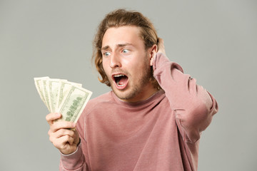 Happy man with money on grey background