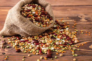 Sack bag with assortment of legumes on wooden table