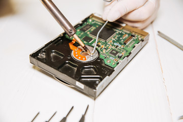 Man repairing hard disk. Inside details of the old personal computer. Broken PC. Soldering iron in...