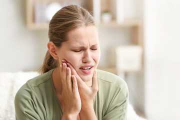 Young woman suffering from toothache at home