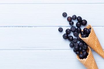Naklejka na ściany i meble Fresh blueberries, in a heart shaped bowl on a wooden background.