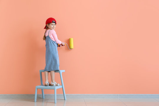 Cute little girl painting wall in room