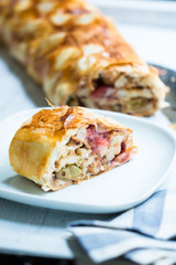 Ein Stück Stachelbeer-Strudel mit ganzem Strudel aufgeschnitten im Hintergrund
