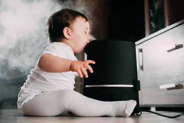 Little baby looks at the humidifier. Moisture in the house concept