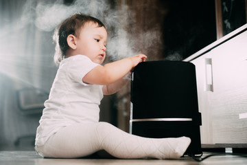 Little baby looks at the humidifier. Moisture in the house concept