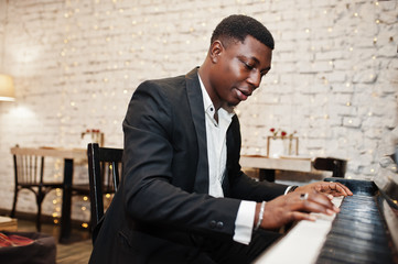 Strong powerful african american man in black suit play piano.