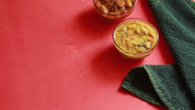 rotation Chole Bhature or Chick pea curry and Fried Puri served in terracotta crockery over red background.