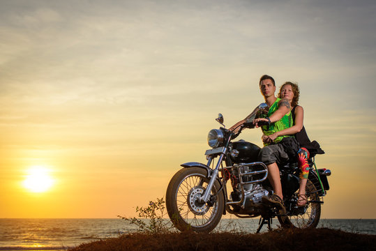 Romantic picture with a couple of beautiful stylish bikers at sunset. Handsome guy with tatoo and young sexy woman enjoy themselves in motorbike trip. © exebiche
