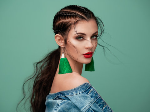 Brunette girl with perfect makeup. Beautiful model woman with curly hairstyle. Care and beauty hair products. Lady with braided hair. Model with jewelry. Turquoise background