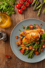 Roasted chicken breast, served on asparagus with tomato sauce, dried tomatoes. Top view.