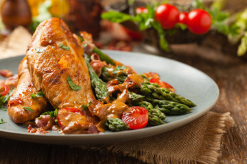 Roasted chicken breast, served on asparagus with tomato sauce, dried tomatoes. Front view.