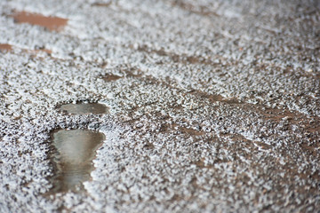 Dent in the form of a trace from the shoes in the asphalt filled with water