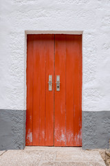 Old red door in a stone building painted white and gray. Background