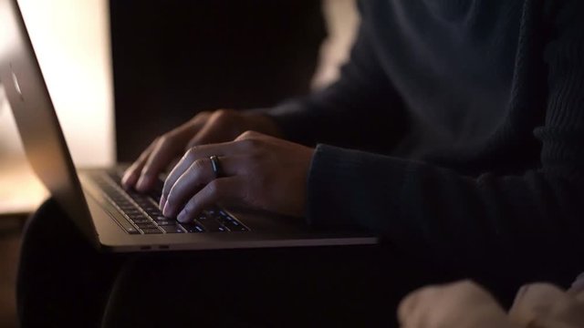 Man typing on computer in his bedroom.