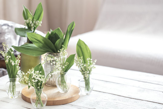 White spring flowers snowdrops in vintage glass bottles on white wooden table, cottage interior decoration