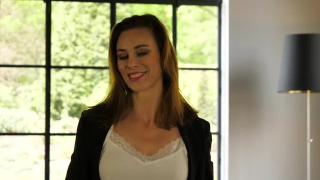 Sensual attractive mature woman going through her hair and smiling in the camera.