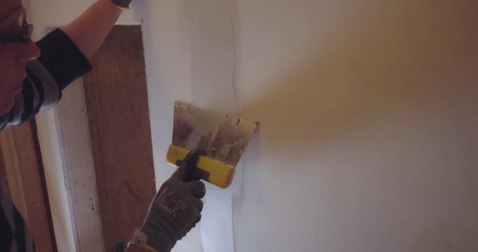 women doing home improvment and renovating a wall with new drywalling and spackle
