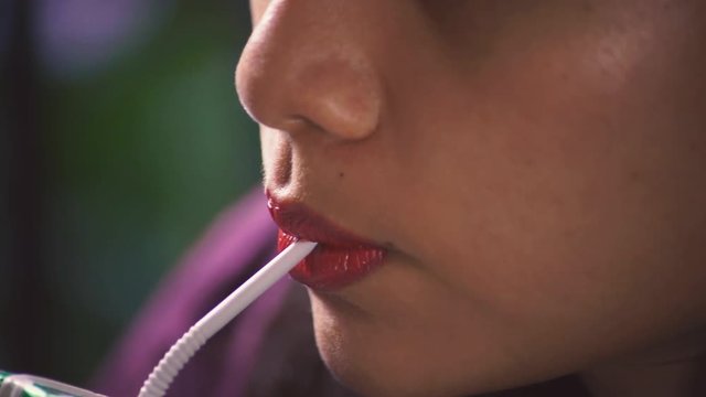 Extreme closeup of a southeast asian girl drinking chocolate milk from carton beverage container using a white plastic straw