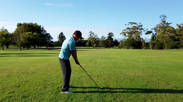 Man on golf course with wood swing and hitting the ball