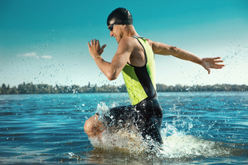 Professional triathlete swimming in river's open water. Man wearing swim equipment practicing...