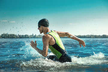 Professional triathlete swimming in river's open water. Man wearing swim equipment practicing...