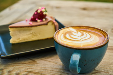 Delicious latte coffee and cheesecake on the wooden table