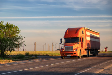 A large red truck transports goods on a long-distance road