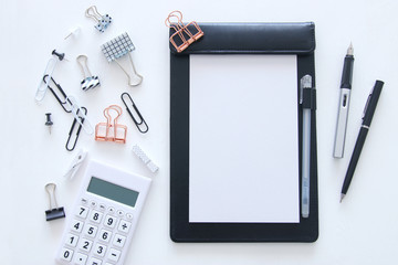 White office desk table with notebook, empty pages and other office supplies. Top view