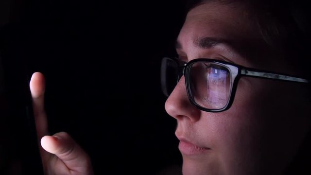 Woman sadly scrolls through social media late at night.