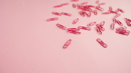 Scattered pink paper clips. Pink background. Flatlay.