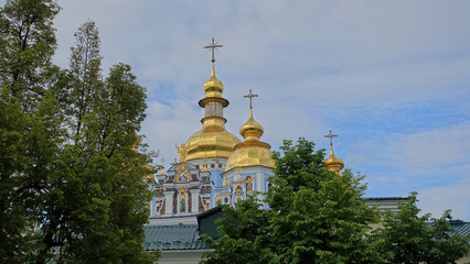 Fototapeta na wymiar The dome of the St. Michael's Golden-domed cathedral among trees