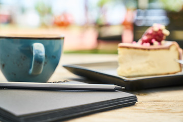 Latte coffee, cheesecake and notebook on the table