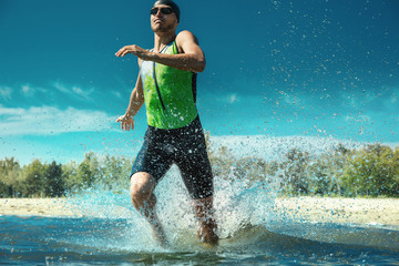 Professional triathlete swimming in river's open water. Man wearing swim equipment practicing triathlon on the beach in summer's day. Concept of healthy lifestyle, sport, action, motion and movement.