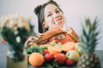 Young woman on a diet succumbed to temptation and passionately bites a white crispy long loaf.