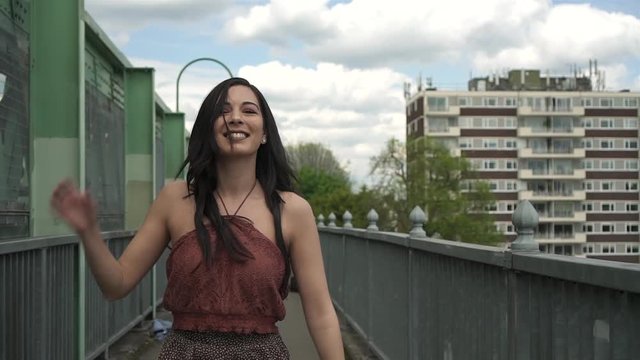 Happy and carefree Latina woman dancing on a bridge in London. Slow motion shot