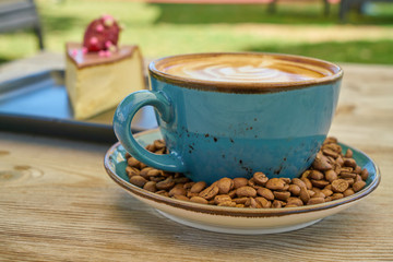 Latte coffee, coffee beans and cheesecake on the wooden table