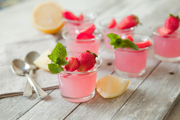 Berry portion jelly in glasses garnished with fresh strawberry and mint. Summer vegan dessert with agar-agar