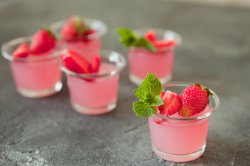 Berry portion jelly in glasses garnished with fresh strawberry and mint. Summer vegan dessert with agar-agar