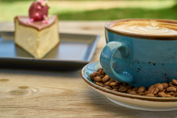 Latte coffee, coffee beans and cheesecake on the wooden table