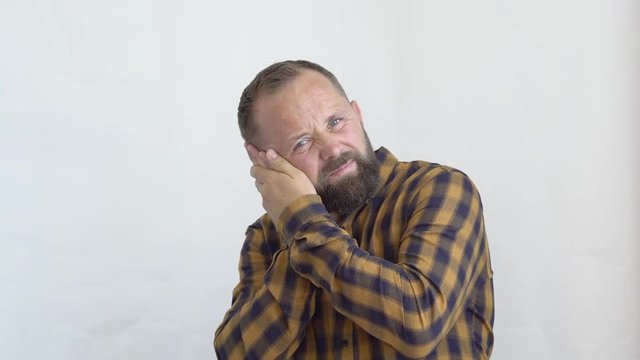 concept of emotions close-up of a bearded man in a plaid shirt on a white background that clings to his right ear ear