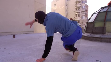 Urban rooftop with man in mask performing parkour and break dancing. Glass dome of a skylight and tall buildings all around. - Powered by Adobe