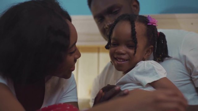 Lovely afro-american young family smiling and huggin together. Close-up of pretty mother and father with little cute girl.